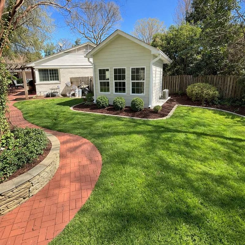 Mulched landscape beds with clean stone edging and a brick walkway