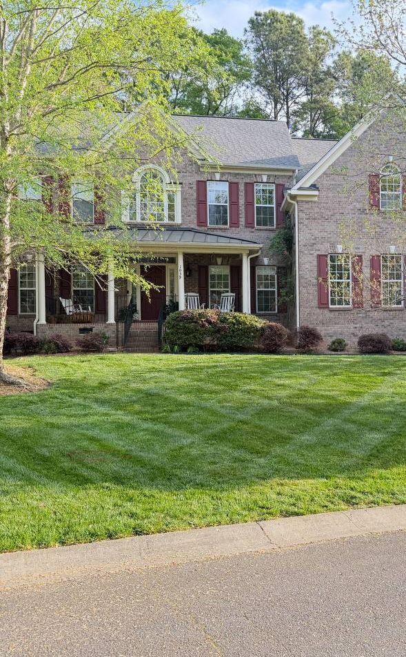 Striped front lawn at a two-story brick home, freshly mowed